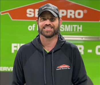 White male smiling in front of SERVPRO truck