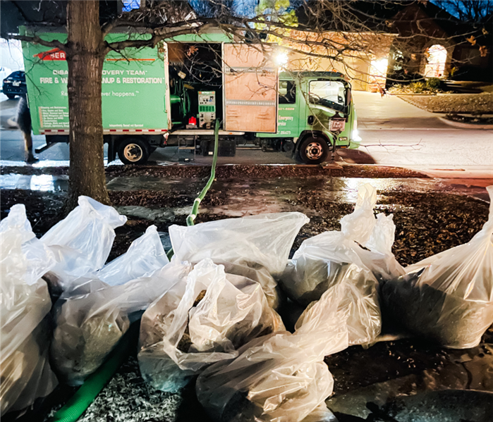 SERVPRO truck in a neighborhood with storm debris stacked up and ready to be loaded.